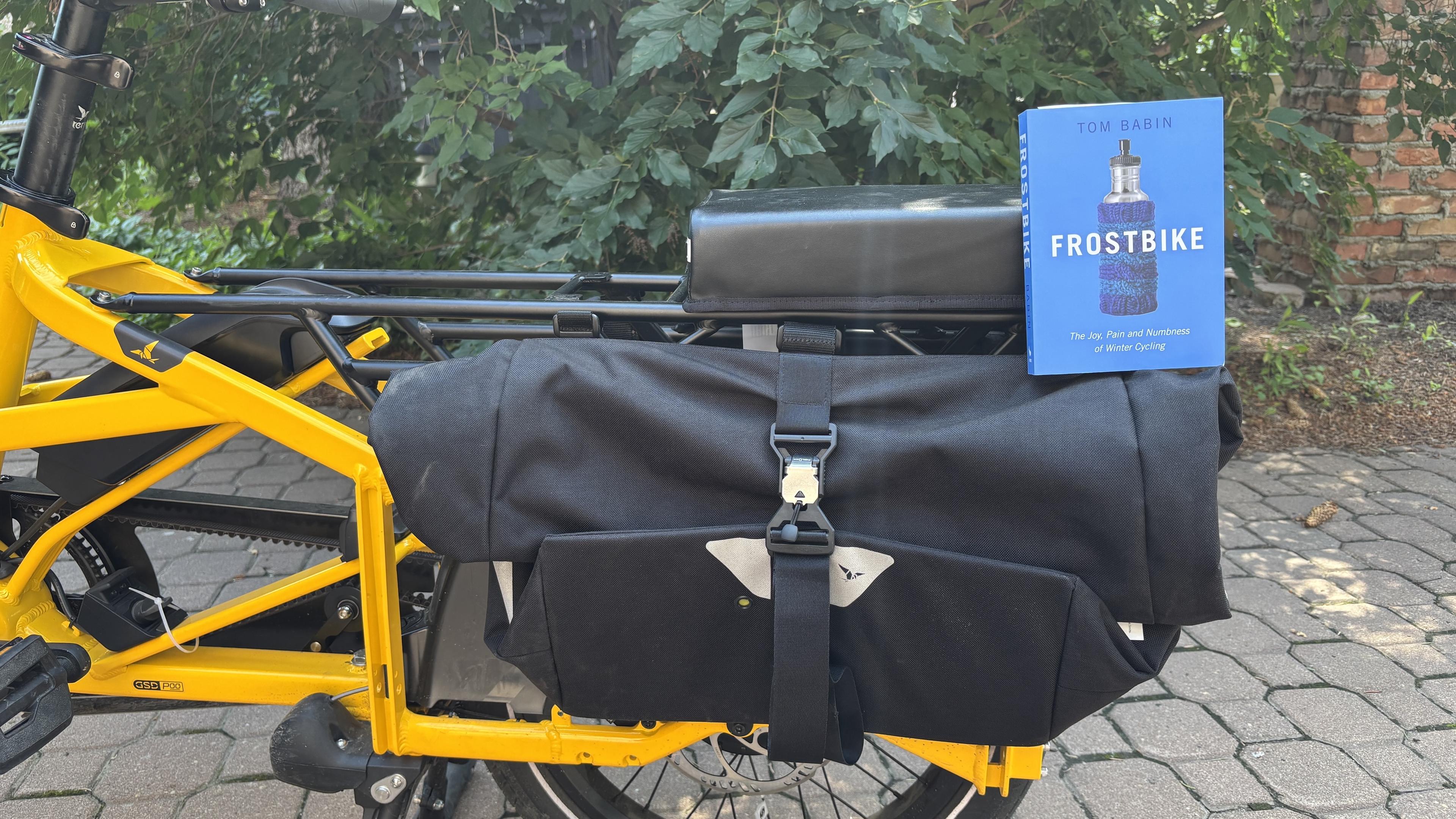 The book, Frostbike, perched on a pannier on the back of a yellow bike